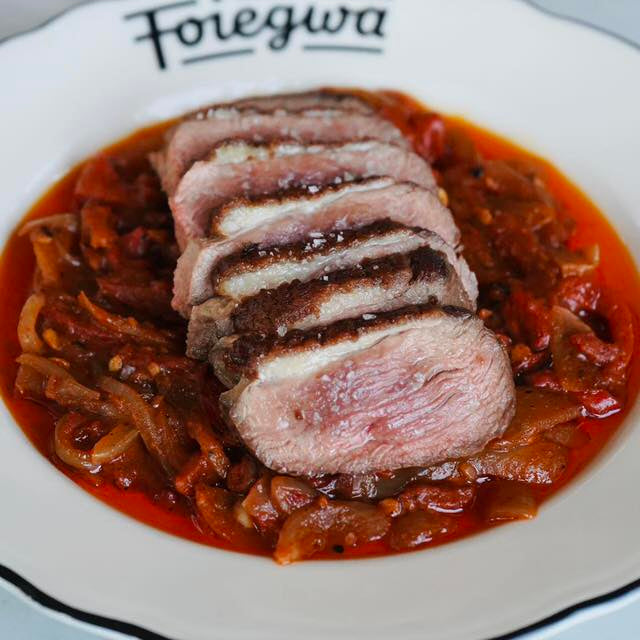 Sliced meat with red sauce on a white plate with 'Foiegwa' branding.