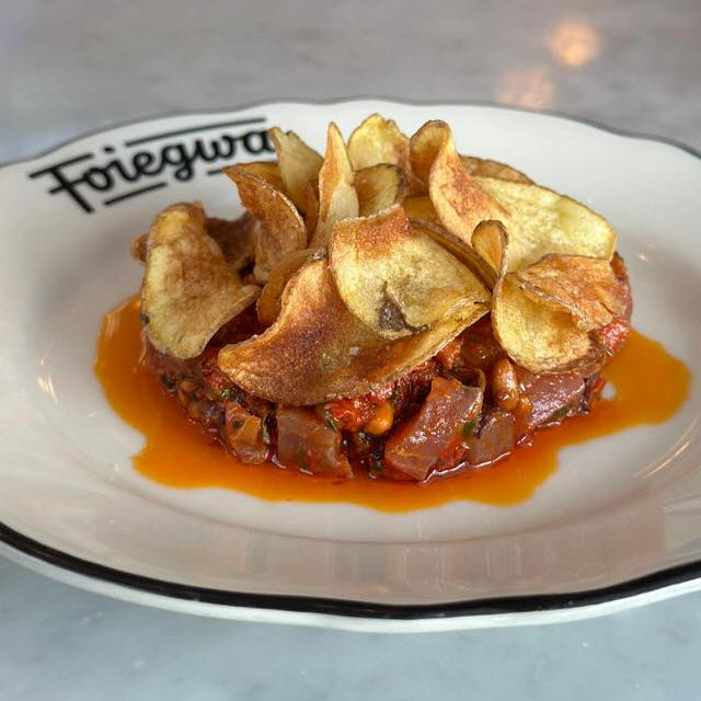 Dish with fried ingredients and red sauce on a white plate with 'Foiegras' branding.